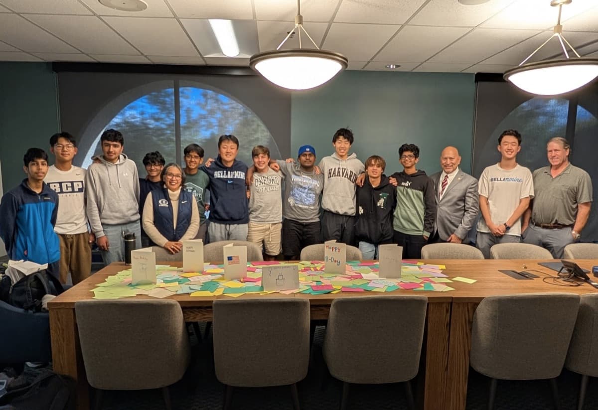 Students and faculty standing behind a conference table covered in signed birthday cards for Corporal Frank Wright.